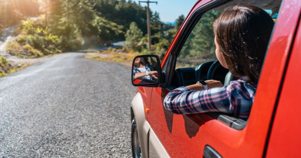 una muchacha conduce por una carretera de montaña